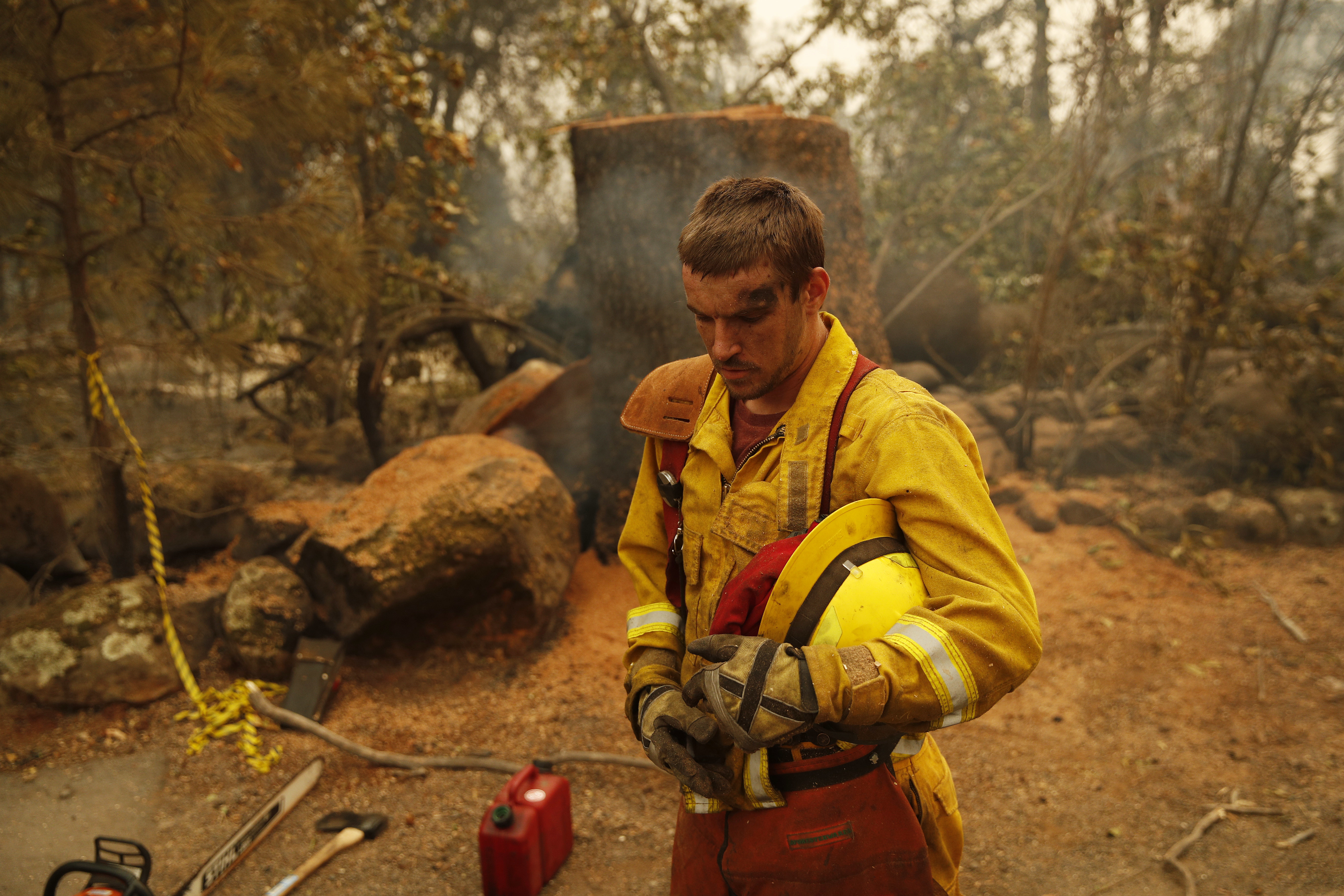 Shawn Slack rests after felling trees burned in the Camp Fire, Monday, Nov. 12, 2018, in Paradise, Calif. (AP Photo/John Locher)