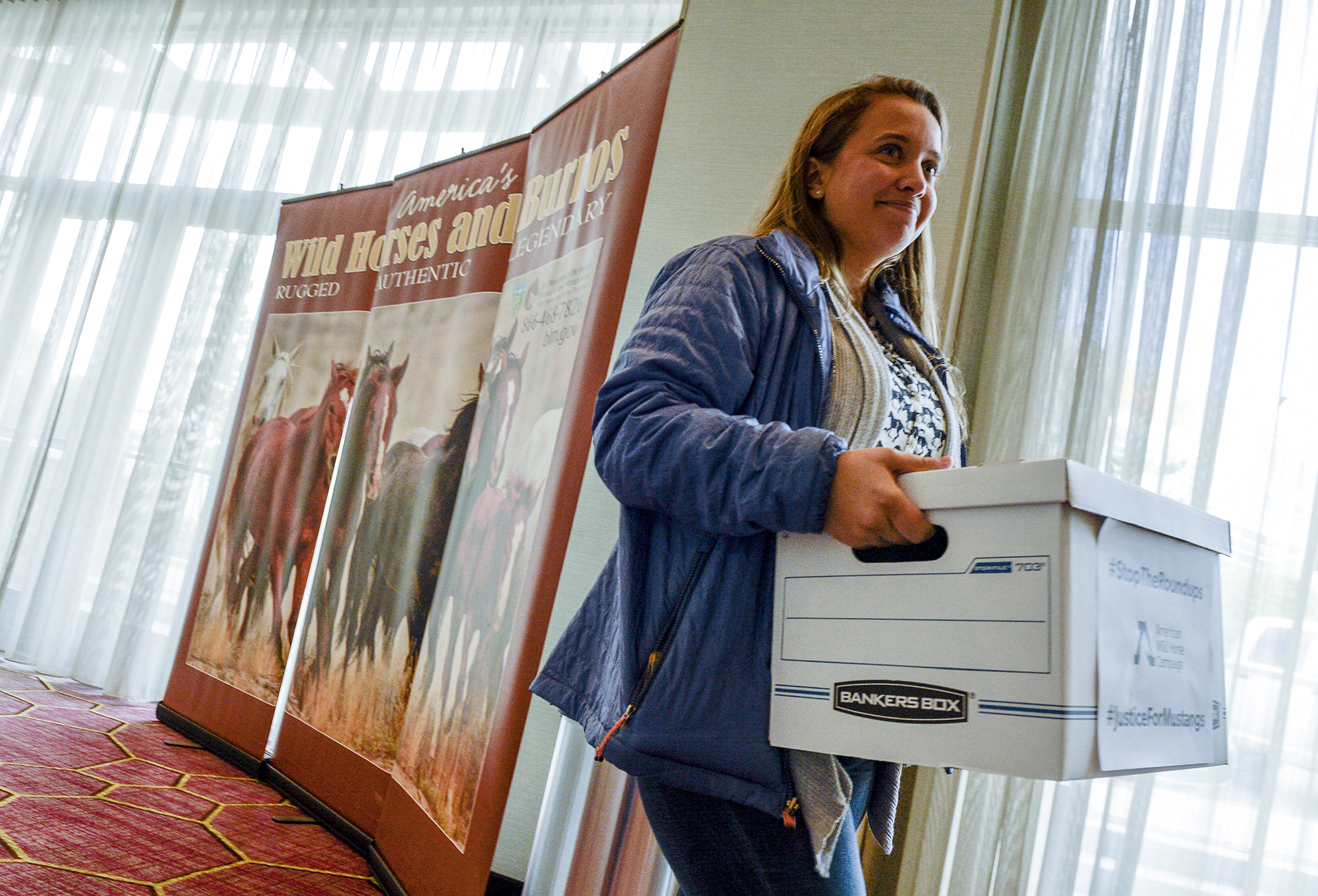 Leah Hogsten | The Salt Lake Tribune l-r Brieanah Schwartz, government relations and policy counsel with the American Wild Horse Campaign, delivers petitions to the BLM's Wild Horse and Burro Advisory Board meeting signed by 250,000 citizens imploring the Bureau of Land Management to stop rounding up wild horses, proposing to sell them to slaughter and sterilizing mares in Salt Lake City, Oct. 10, 2018.