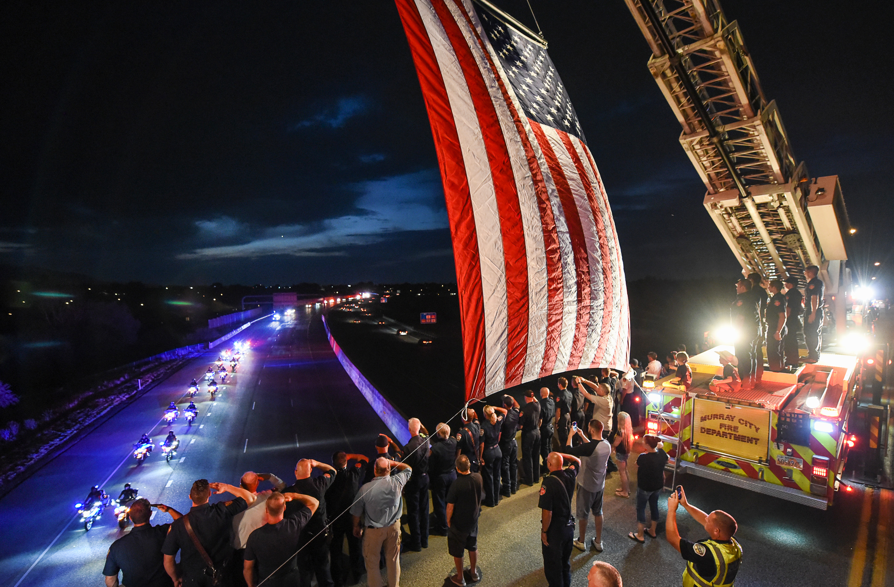 (Francisco Kjolseth | The Salt Lake Tribune) The body of Utah firefighter Matt Burchett, 42, who died fighting a wildfire in California is honored by a firefighter detail along Murray Parkway as his body is returned home, traveling along I-215 after being flown in to the Utah Air National Guard in Salt Lake City on Wed. Aug. 15, 2018. The remains of the Draper battalion chief were transported to Jenkins-Soffe Mortuary in South Jordan.