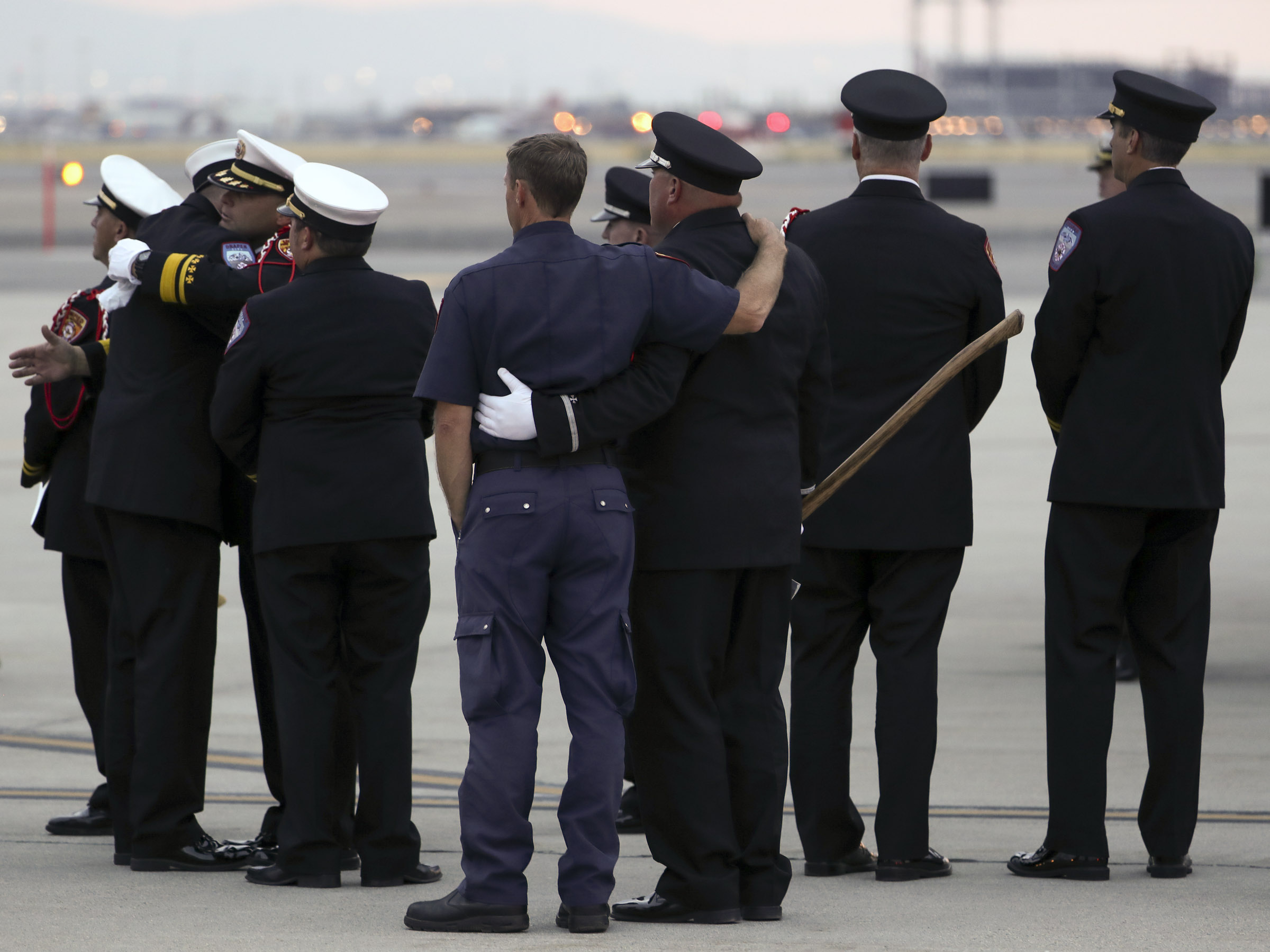 (Steve Griffin | Deseret News, pool photo) Members of the Draper City Fire Department and Unified Fire Authority Honor Guard stand with family members after the casket of Draper Battalion Chief Matt Burchett is placed in a hearse after being transported from California to Utah in a C130-J by the California Air National Guard. The C130-J landed at the Utah Air National Guard Base in Salt Lake City on Wednesday, Aug. 15, 2018. Burchett was killed while fighting the Mendocino Complex Fire north of San Francisco.