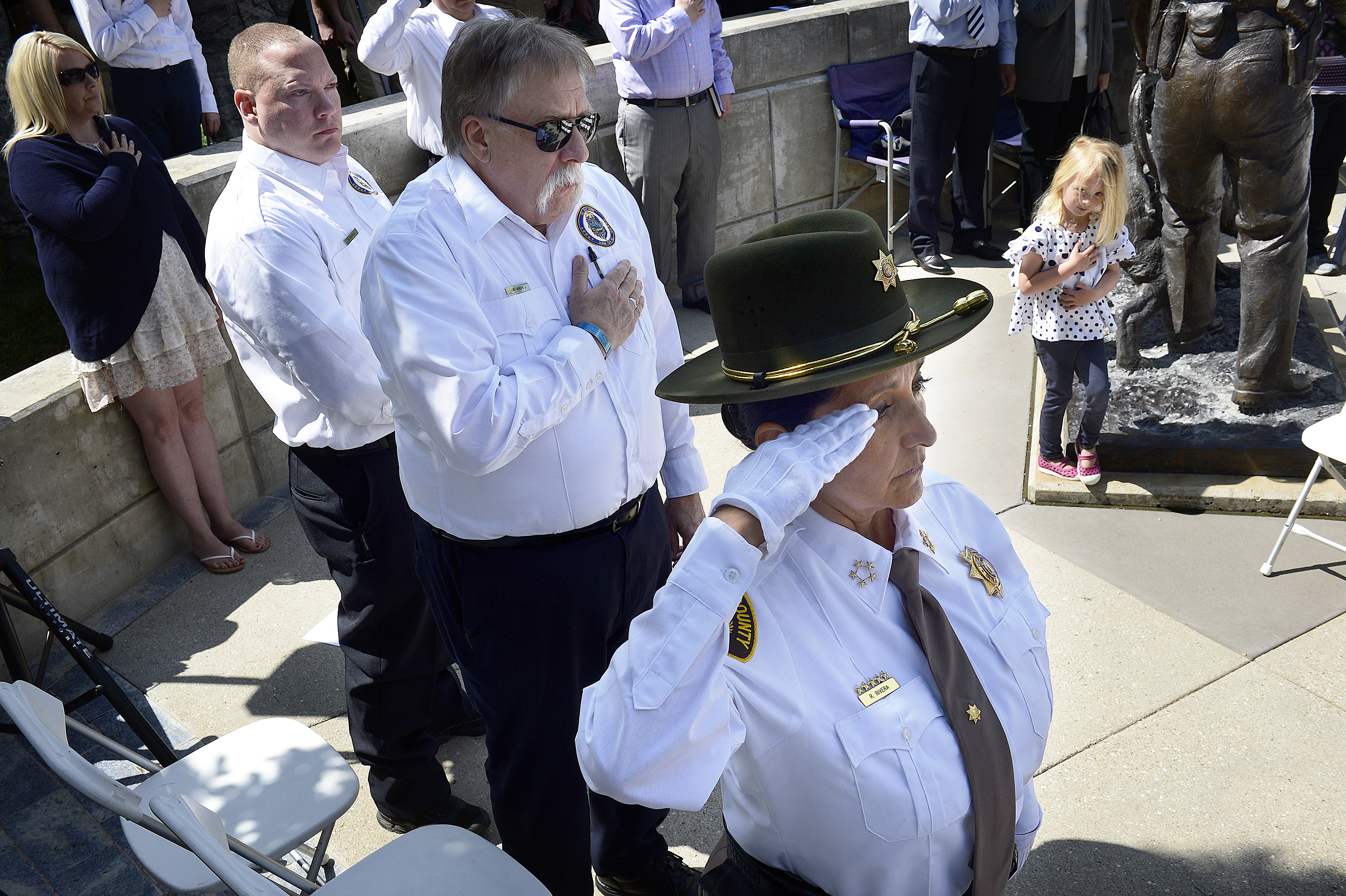 (Scott Sommerdorf | The Salt Lake Tribune) Salt Lake Tribune columnist Robert Kirby, center, and Salt Lake County Sheriff Rosie Rivera saluted as the colors are struck at the Utah Law Enforcement Memorial to honor the 142 police officers killed in the line of duty during the state's history, Thursday, May 3, 2018. No Utah law enforcement officer died in the line of duty last year.