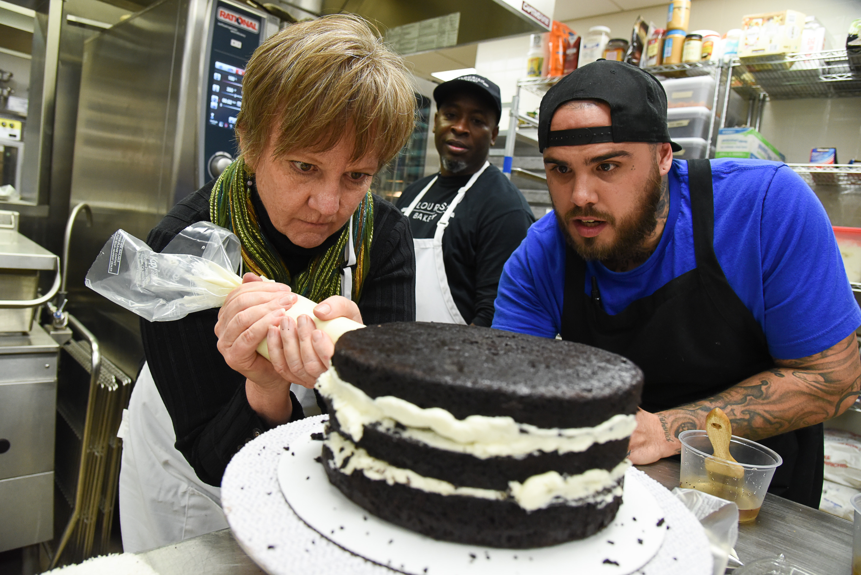 (Francisco Kjolseth | The Salt Lake Tribune) Actress Betsy West got a little guidance with frosting a cake from chefs Frederick Jackson, center, and A.J. Collette as she prepared to play a Southern Baptist bakery owner in North Carolina faced with a request to bake a wedding cake for a gay couple. She appears in Salt Lake Acting Company's production of "The Cake." A self-admitted baking novice, West was in search of better authenticity and received lessons from chefs at Flourish.