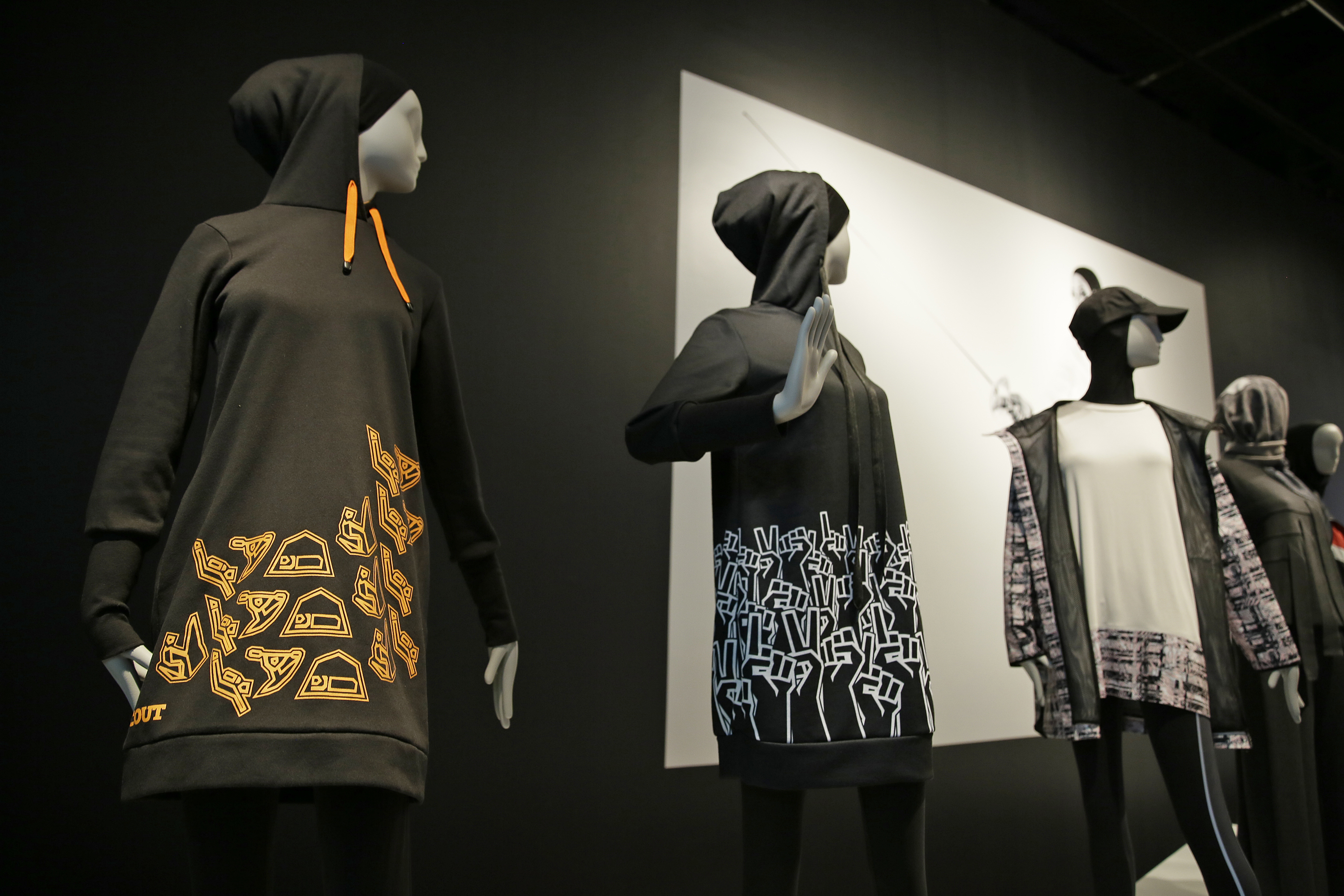 In this photo taken Thursday, Sept. 20, 2018, is a hooded knee-length dress at left made by Sarah Elenany for Muslim Girls, who wanted to participate in the Scout Association of the United Kingdom, in the exhibit Contemporary Muslim Fashions at the M. H. de Young Memorial Museum in San Francisco. The first major museum exhibition of contemporary Muslim women's fashion reflects designs from around the world that are vibrant and elegant, playful and diverse. The exhibit opens on Saturday. (AP Photo/Eric Risberg)