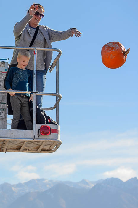 (Trent Nelson | The Salt Lake Tribune) Kimberly Powell drops a pumpkin at Glover Nursery in West Jordan on Saturday Nov. 3, 2018. Watching are James Sparks, left, and Owen Powell. The nursery held its annual pumpkin smash and food drive, dropping pumpkins from a cherry picker and collecting donations for the needy.