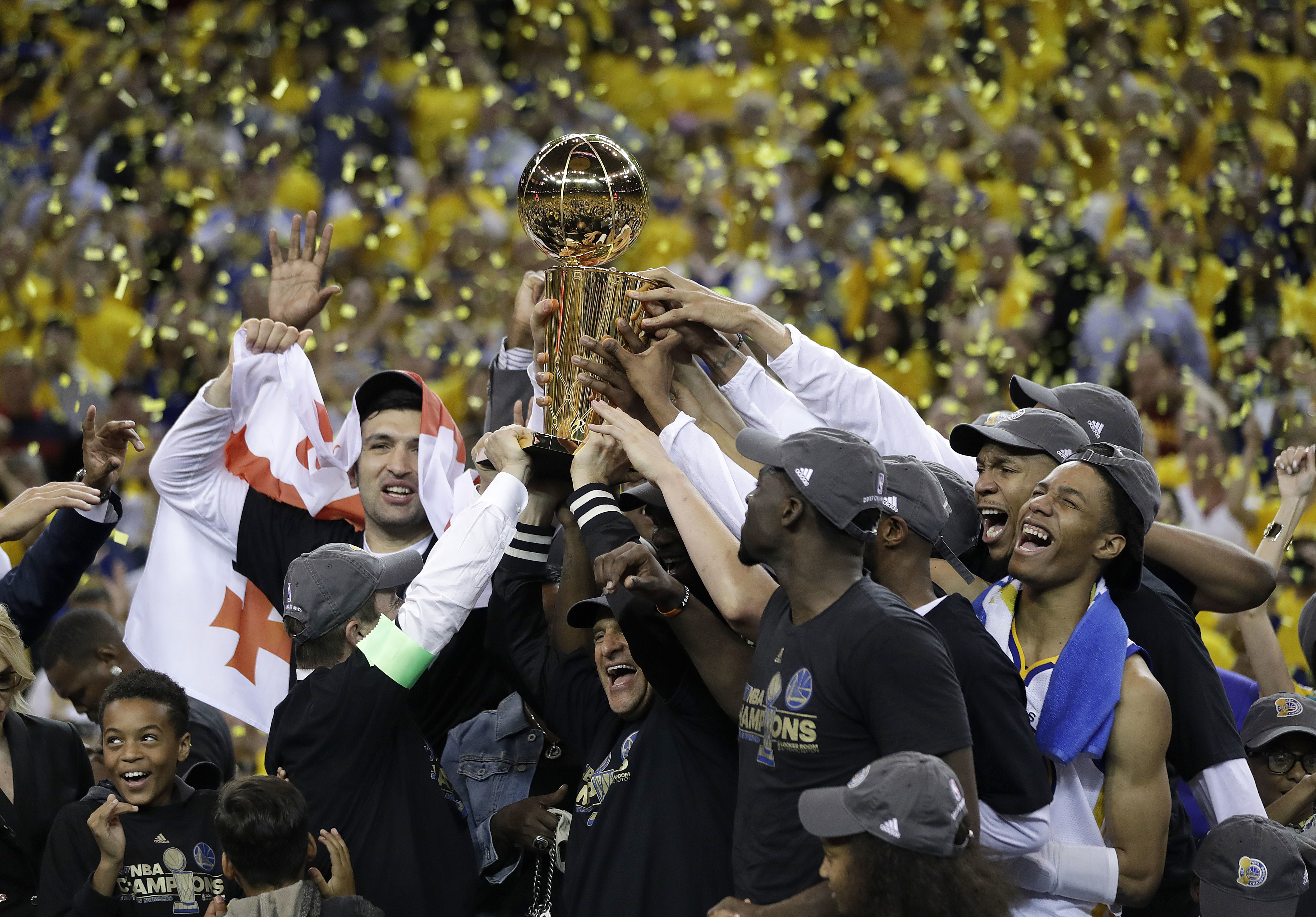 FILE - In this June 12, 2017, file photo, Golden State Warriors players, coaches and owners hold up the Larry O'Brien NBA Championship Trophy after Game 5 of basketball's NBA Finals between the Warriors and the Cleveland Cavaliers in Oakland, Calif. Winners of the NBA title in two of the last three seasons, Golden State made it look easy at times a year ago and prevailed in 31 of its final 33 games. (AP Photo/Marcio Jose Sanchez, File)