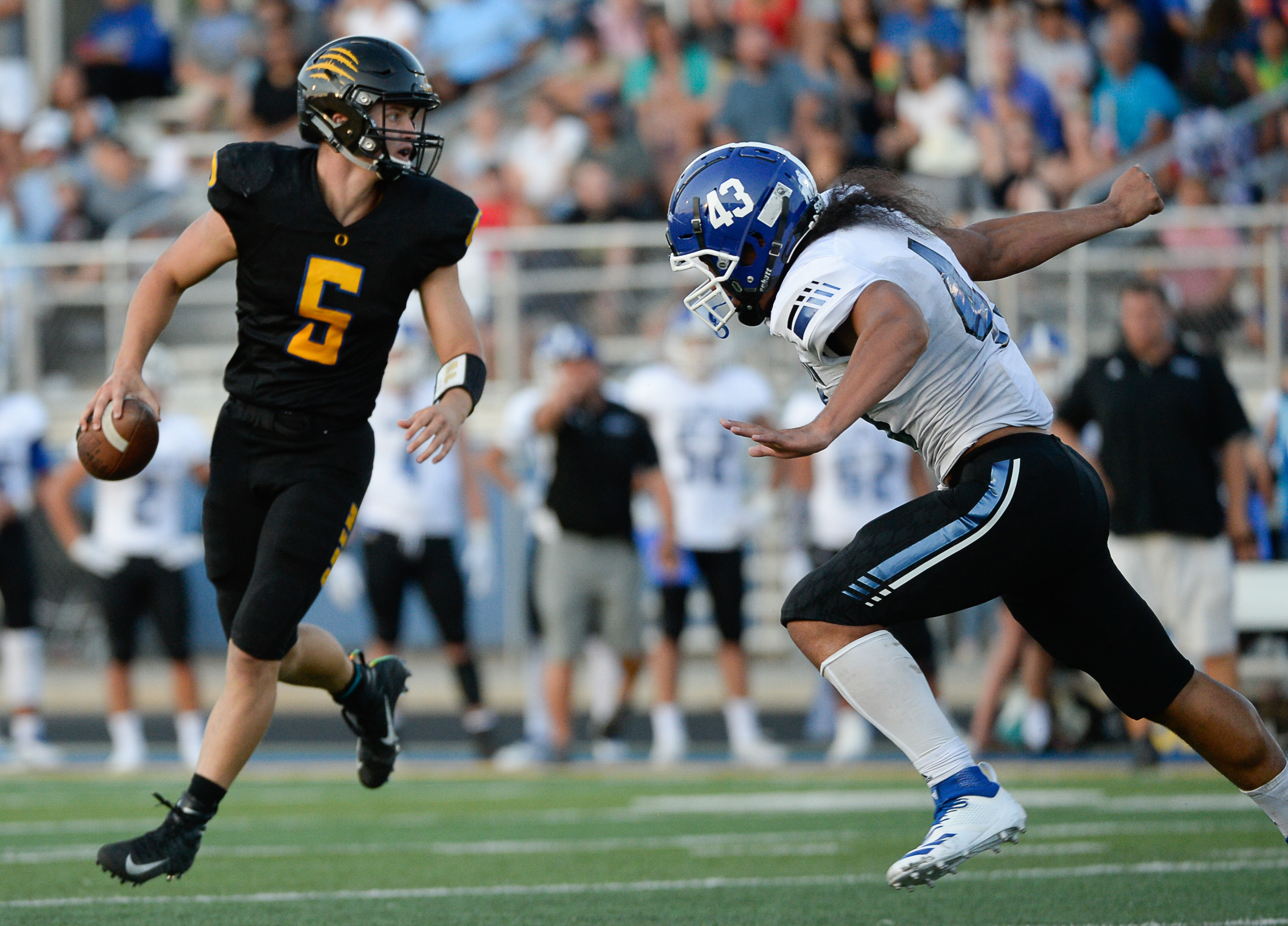 (Francisco Kjolseth | The Salt Lake Tribune) Orem quarter back Cooper Legas is pressured by Orem's Lolani Langi for the start of the football season in Orem on Thursday, Aug. 16, 2018.