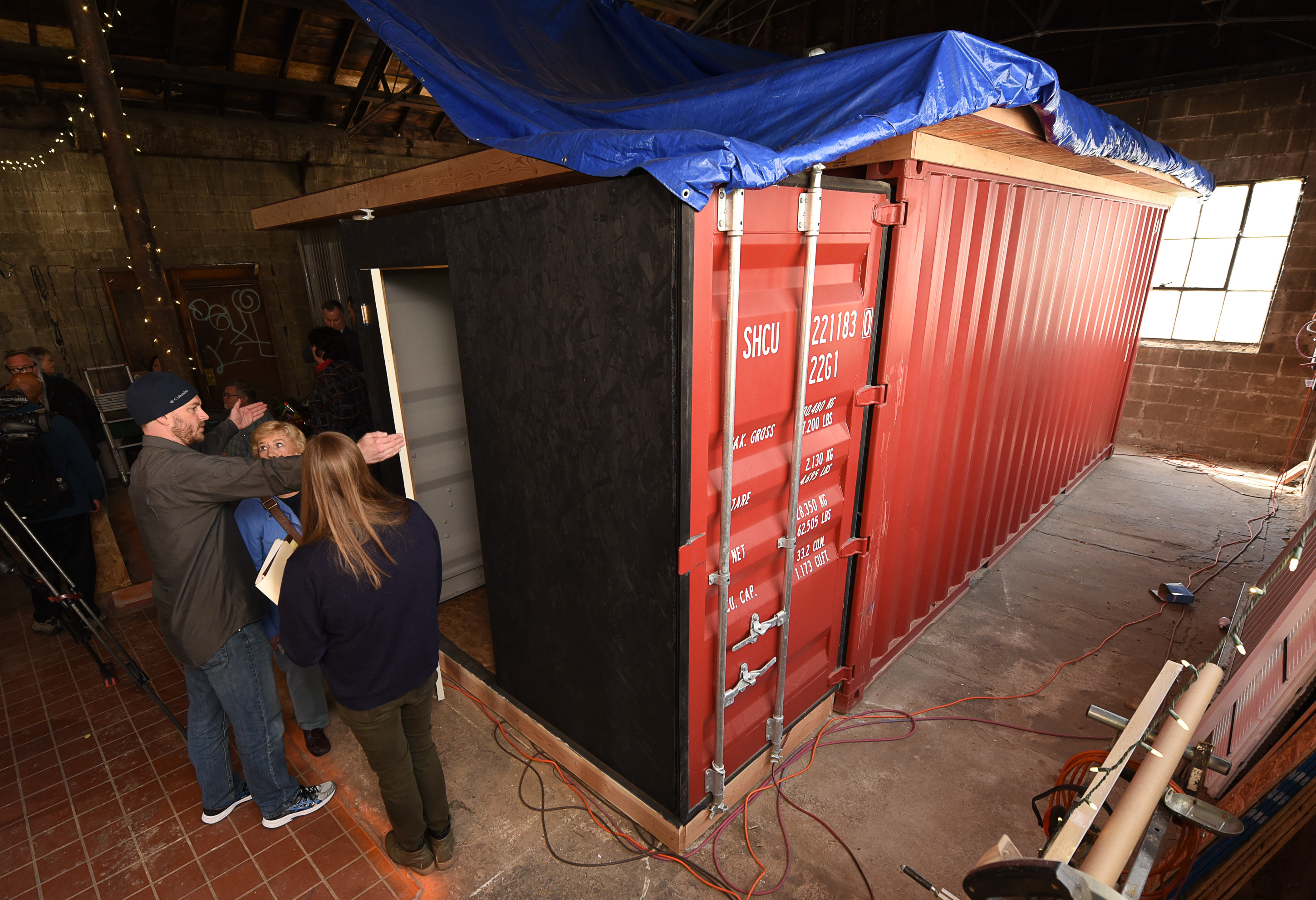 (Francisco Kjolseth | The Salt Lake Tribune) People tour a shipping container home and the enclosure built within the swinging doors to provide storage space. Our Homes, Our Voices, a campaign to bring more attention to the affordable housing crisis across the country showcases one of the solutions being presented by small house specialist Jeff White in Sat Lake City on Wed. May 2, 2018. White has been investing his time now for several years on shipping container prototypes, including a 432 square foot experimental home he built inside a warehouse in Salt Lake that would cost about $36,000 and be easy to assemble on a lot.