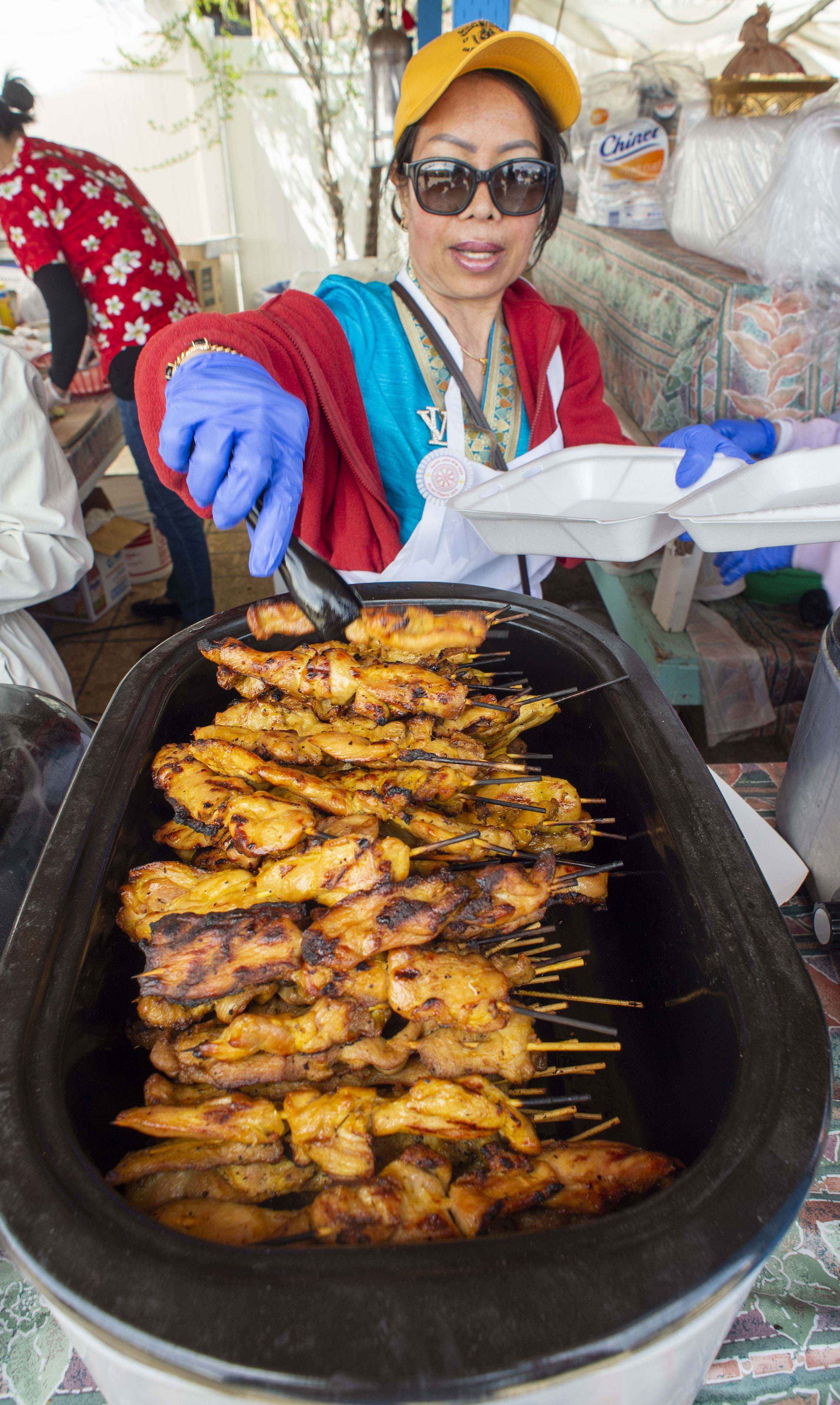 (Rick Egan | The Salt Lake Tribune) Khamvang Kaykeo dishes up some grilled chicken, during the Wat Lao Salt Lake Buddharam Utah, New Year Celebration, in West Valley City, Sunday, April 28, 2019. 