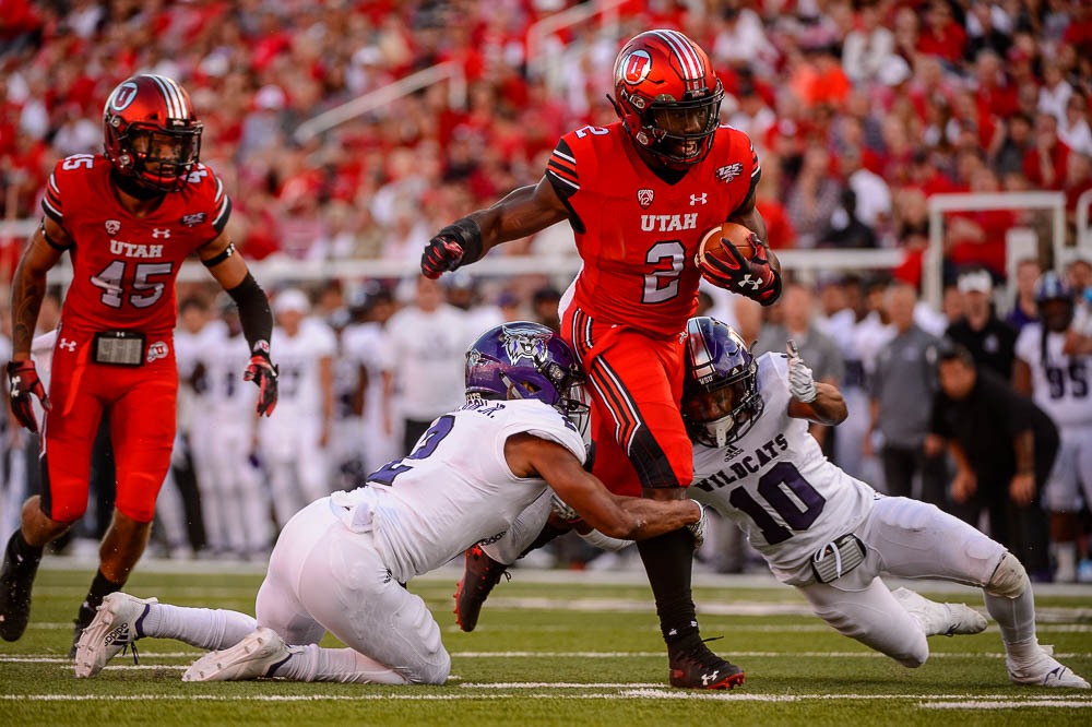 (Trent Nelson | The Salt Lake Tribune) Utah Utes running back Zack Moss (2) runs between Weber State Wildcats safety Jawian Harrison Jr. (2) and Weber State Wildcats cornerback Keilan Benjamin (10) as the University of Utah Utes host the Weber State Wildcats, Thursday Aug. 30, 2018 at Rice-Eccles Stadium in Salt Lake City.