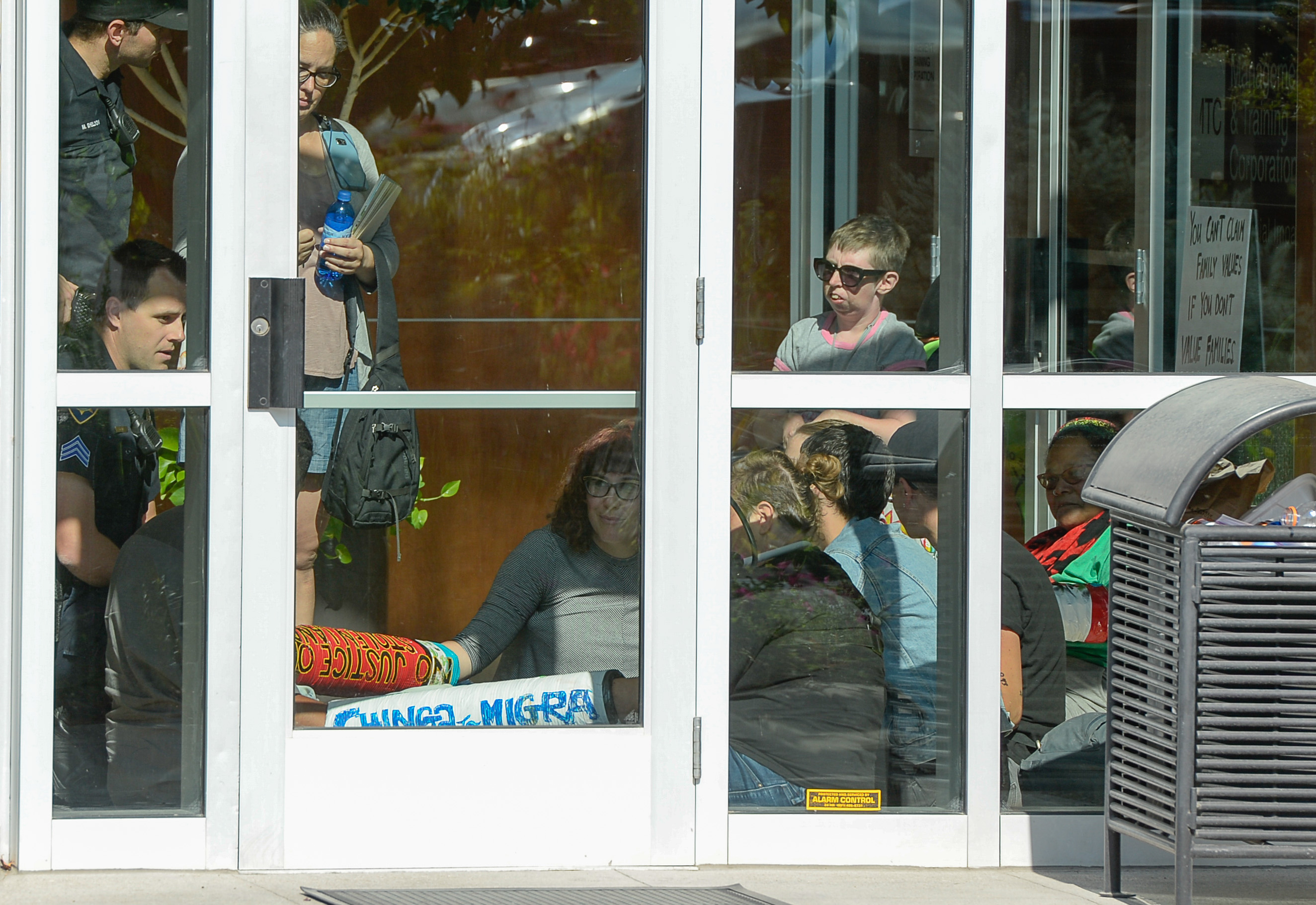 (Francisco Kjolseth | The Salt Lake Tribune) Activists stage a protest against a private prison company with contracts to hold undocumented immigrants on Thursday, July 12, 2018, after locking themselves in the lobby at the headquarters of Management and Training Corporation in Centerville.