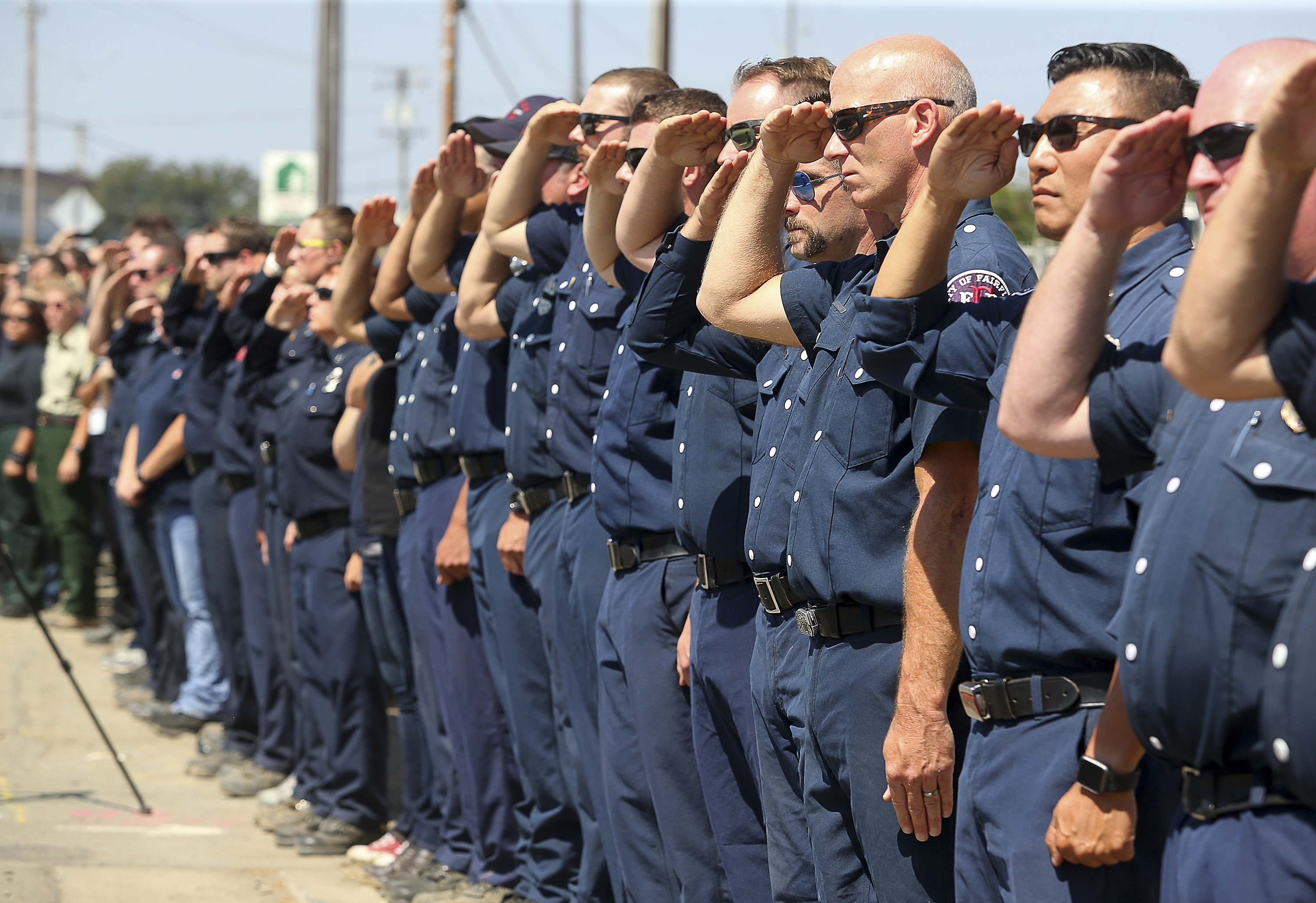 (Christopher Chung | The Press Democrat via AP) Firefighting personnel from various agencies salute as the procession for Battalion Chief Matthew Burchett travels along North State Street, in Ukiah, Calif., on Wednesday, Aug. 15, 2018. Burchett said goodbye to his wife and 7-year-old son in early August, volunteering to travel with fellow firefighters from Utah to help battle record-setting blazes in California. Burchett was hit by a falling tree and died Monday night while fighting the largest blaze in California history, the Mendocino Complex fire north of San Francisco.