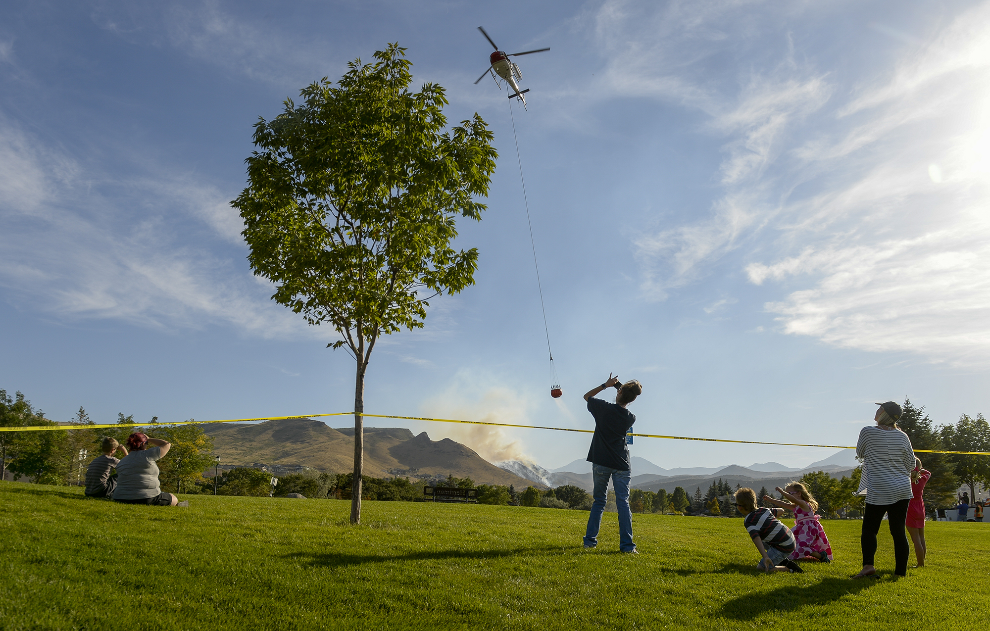 Leah Hogsten | The Salt Lake Tribune Homeowners who were not allowed to return to their homes and onlookers waited near Herriman Cove pond to watch as a firefighting helicopter refilled. A 50-acre wildfire in Rose Canyon was threatened about a half-dozen homes Wednesday, Sept. 12, 2018. A spokesman for Unified Fire said the blaze has already burned a few structures, including outhouses and sheds. Firefighters have evacuated around 20 to 30 homes in two neighborhoods near 15555 S. Rose Canyon Road in Herriman. 