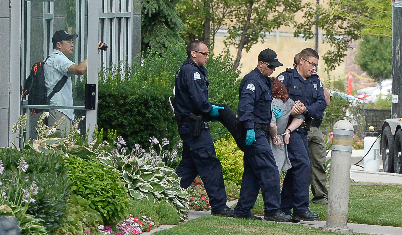 (Francisco Kjolseth | The Salt Lake Tribune) Activists are escorted out of a building where they staged a protest against a private prison company with contracts to hold undocumented immigrants on Thursday, July 12, 2018, at the headquarters of Management and Training Corporation in Centerville.