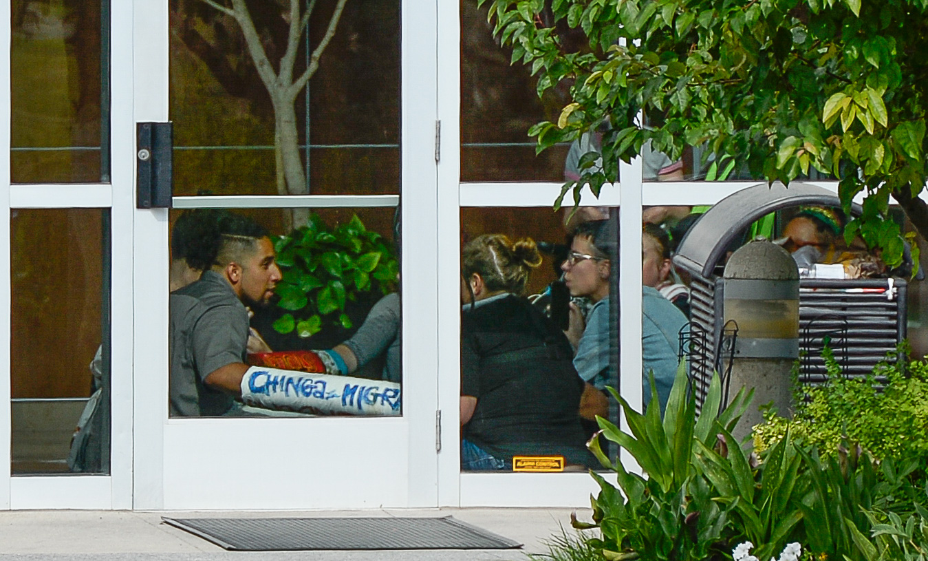 (Francisco Kjolseth | The Salt Lake Tribune) Activists stage a protest against a private prison company with contracts to hold undocumented immigrants on Thursday, July 12, 2018, after locking themselves in the lobby at the headquarters of Management and Training Corporation in Centerville.