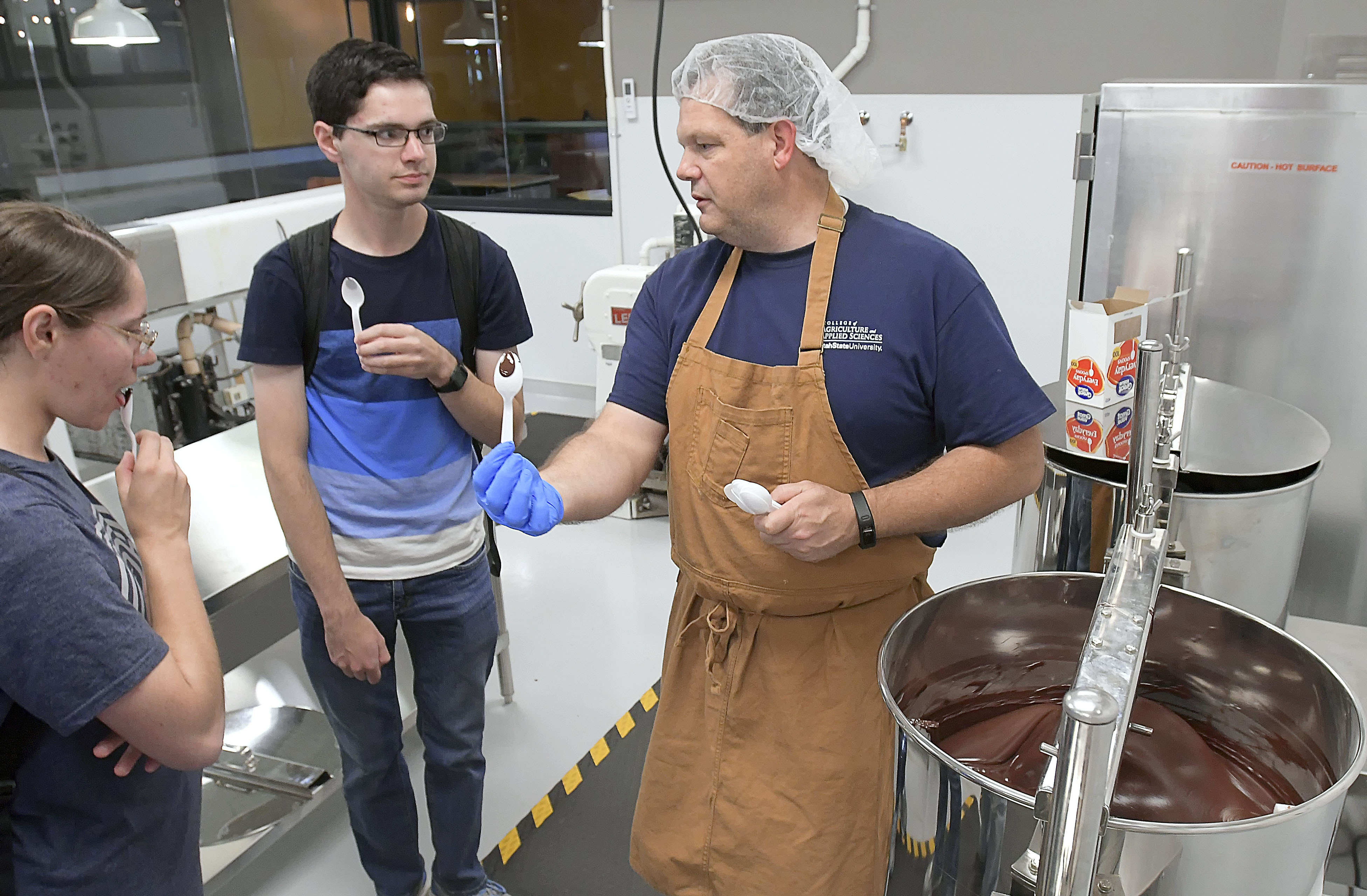 (Eli Lucero | The Herald Journal) Steve Shelton, right, talks to Akyra Winsor and Cameron Winsor while handing out samples during a public tour of the Aggie Chocolate Factory on Tuesday in Logan.