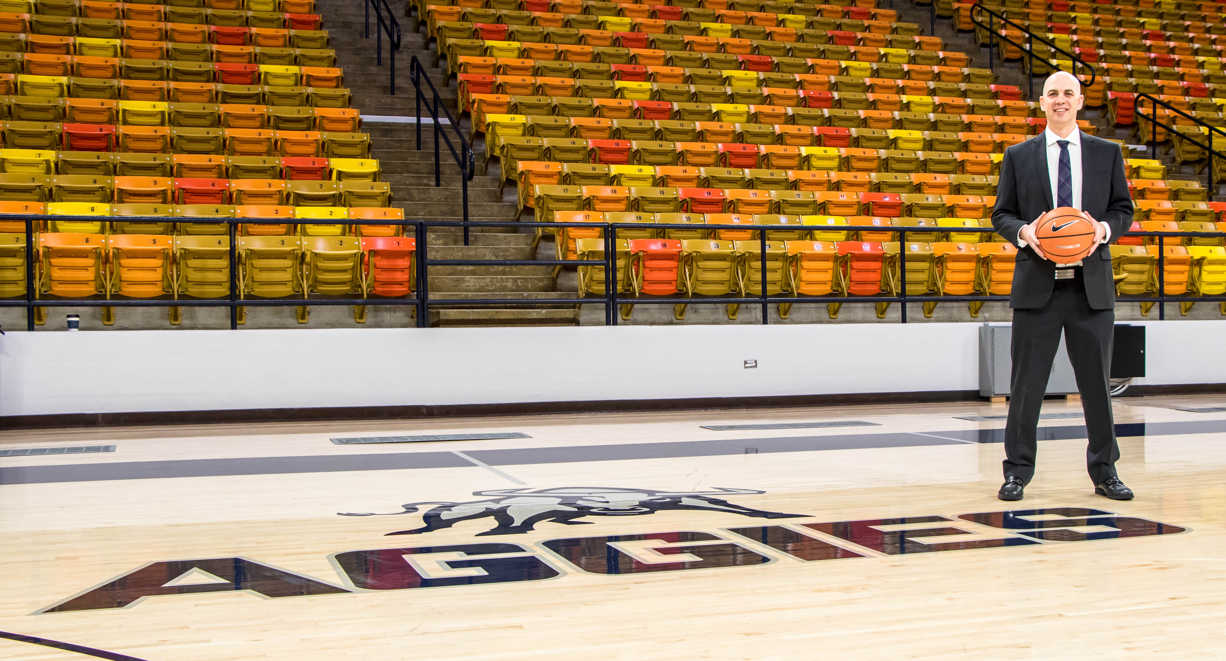 Photo courtesy USU athletics: New Utah State men's basketball coach Craig Smith poses on the court inside the Dee Glen Smith Spectrum in Logan. Smith was hired in March.