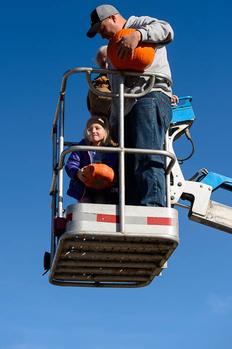 (Trent Nelson | The Salt Lake Tribune) Kaycee Powell throws a pumpkin, with her dad Nate looking on, at Glover Nursery in West Jordan on Saturday Nov. 3, 2018. The nursery held its annual pumpkin smash and food drive, dropping pumpkins from a cherry picker and collecting donations for the needy.