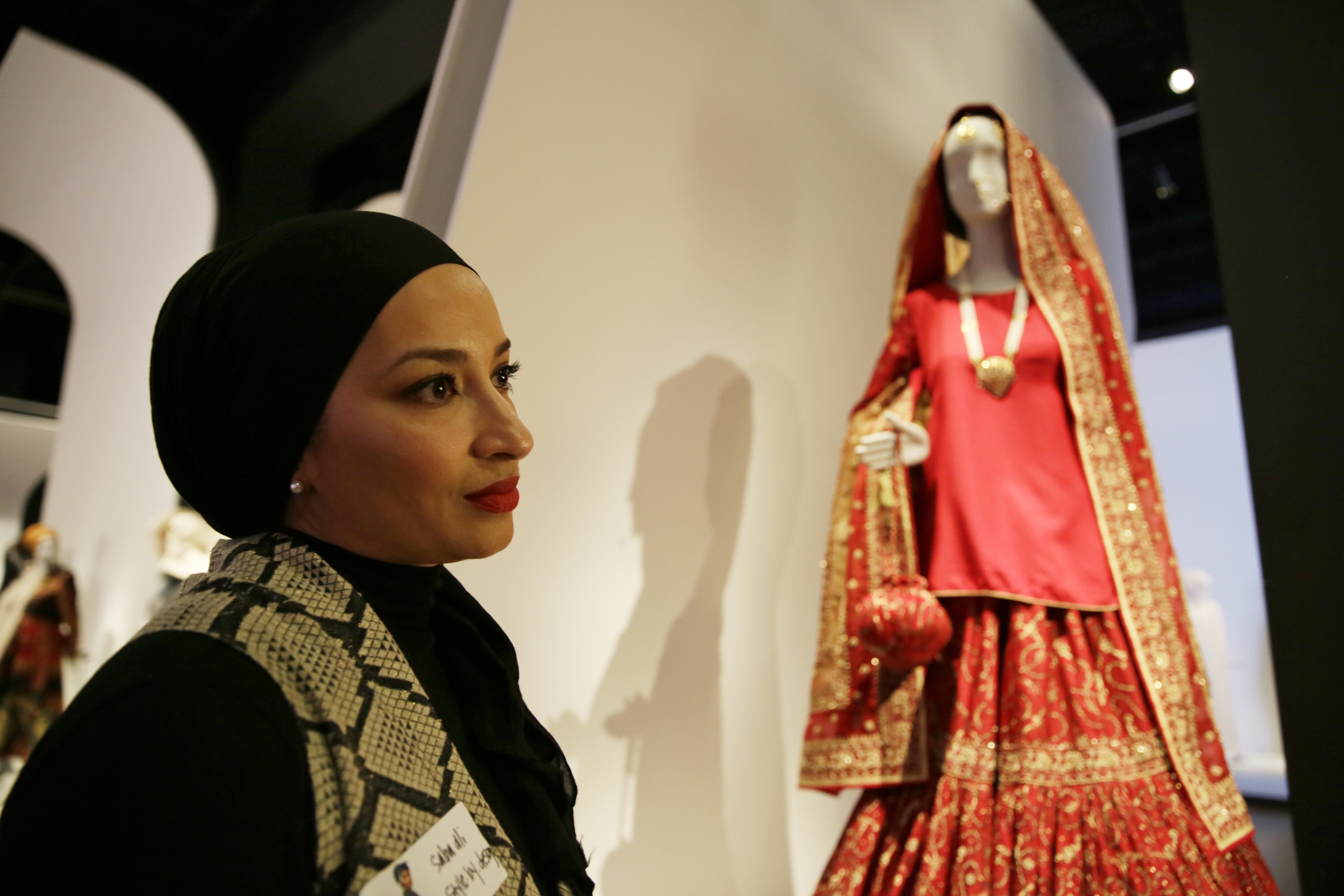 (Eric Risberg | AP Photo) In this photo taken Thursday, Sept. 20, 2018, stylist Saba Ali talks about her Pakistani wedding ensemble of red silk and chiffon in the exhibit Contemporary Muslim Fashions at the M. H. de Young Memorial Museum in San Francisco. The first major museum exhibition of contemporary Muslim women's fashion reflects designs from around the world that are vibrant and elegant, playful and diverse. The show's creators hope the exhibit will show Muslim women as real people who can choose what they wear rather than as subjects ordered to cover their entire bodies or restricted in what they can wear. The exhibit opens on Saturday.