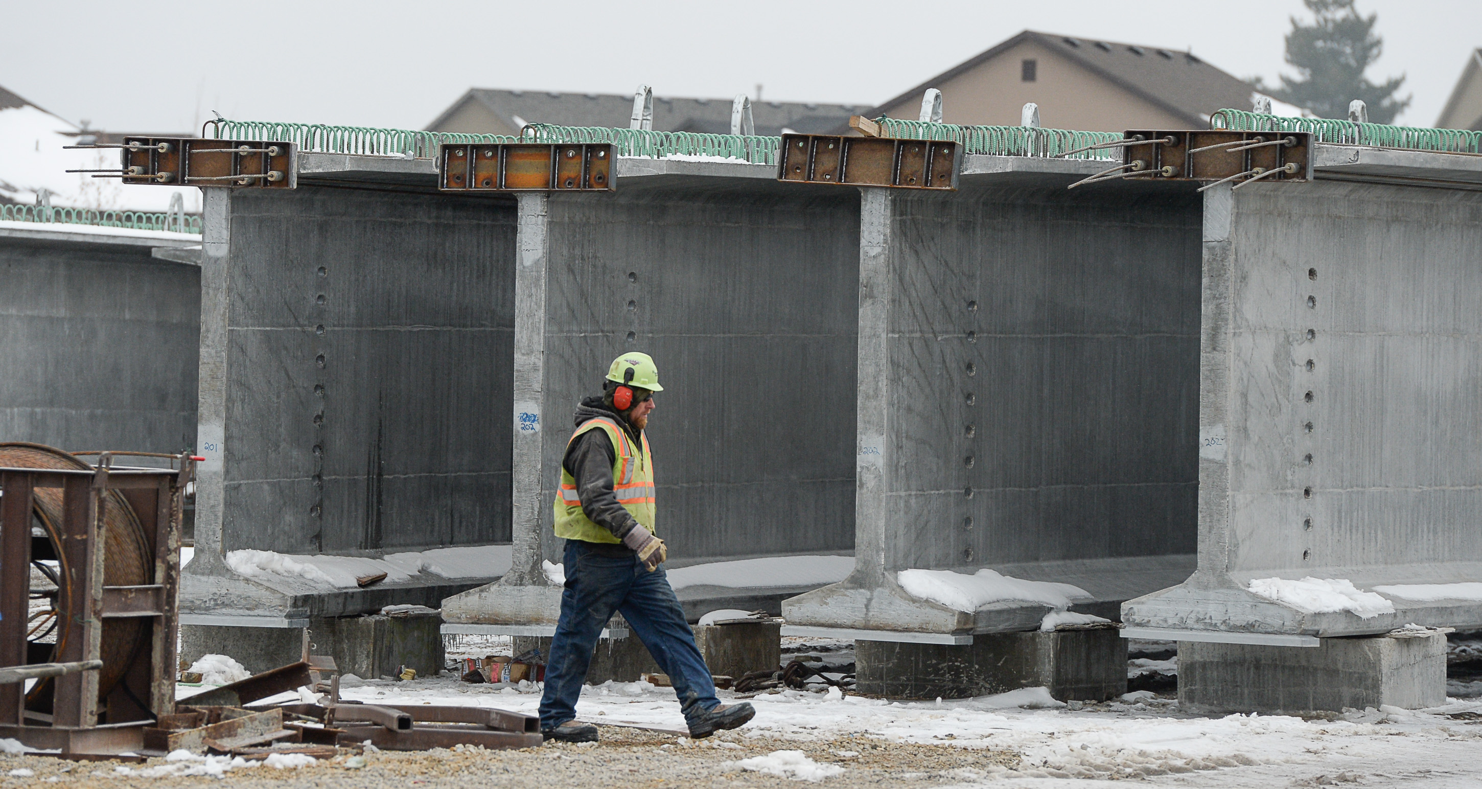 (Francisco Kjolseth | The Salt Lake Tribune) A crew member walks amongst the giants as UDOT gets ready to place some of the world's largest-ever bridge beams, and the largest in Utah state history, with a span of 203 ft long and just over 8 ft tall. Crews began to load the pieces following manufacturing at Forterra Structural Precast in Kearns on Tuesday, Dec. 11, 2018. A total of six beams will be installed in the technology corridor in Lehi later this week.