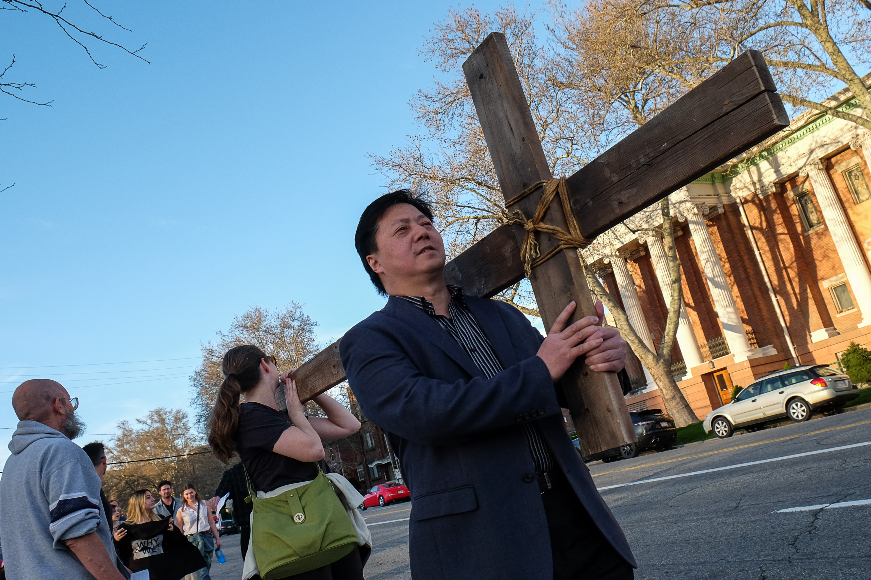 (Francisco Kjolseth | The Salt Lake Tribune) Yichen Lee joins other christians as they march through streets of Salt Lake City on Good Friday to symbolically mark Jesus' carrying the cross to his crucifixion beginning at Cathedral of the Madeleine.