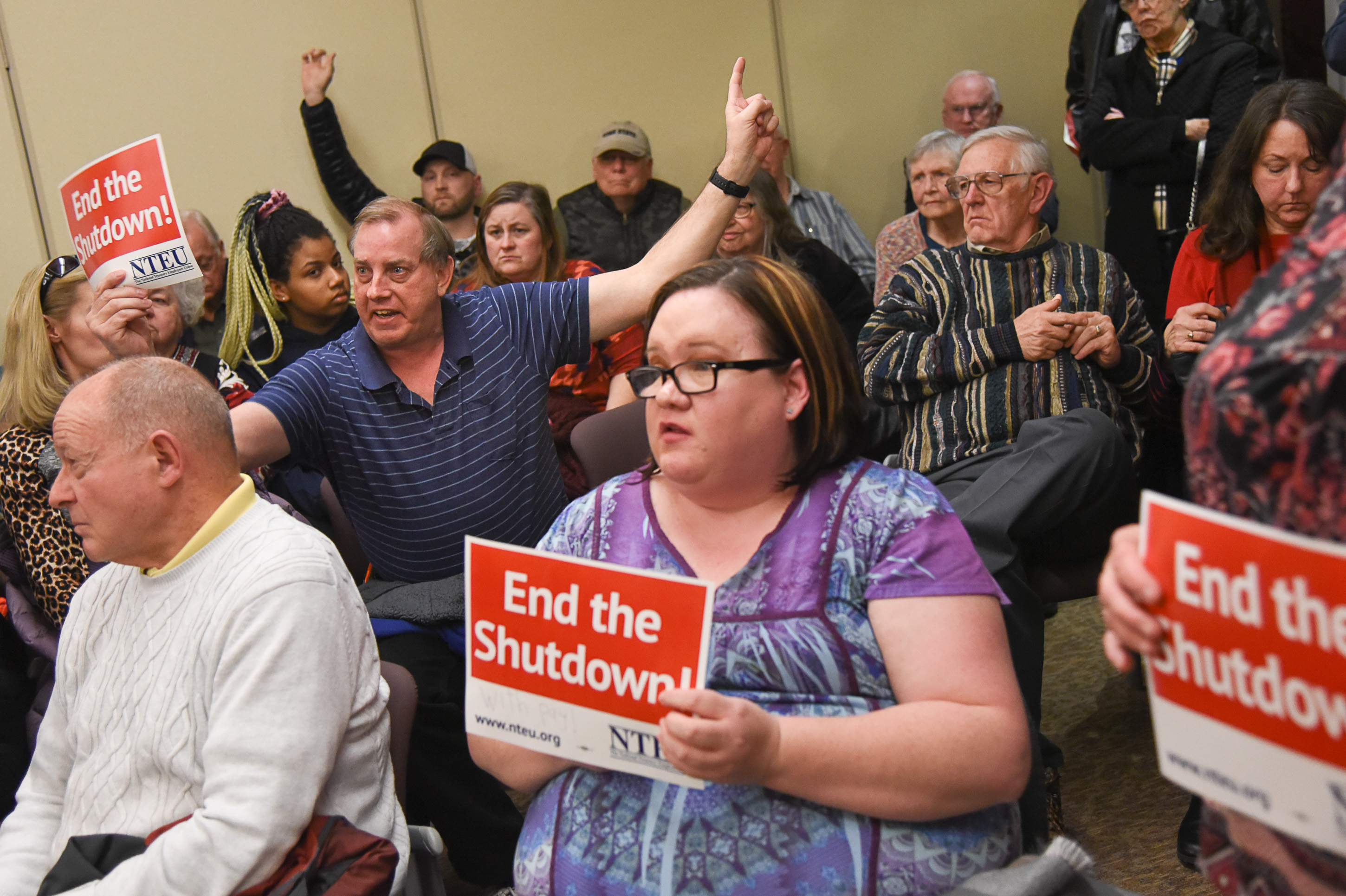(Francisco Kjolseth | The Salt Lake Tribune) Gordon McKinney, left, a federal worker with the IRS in Ogden shouts out his claim that a colleague with diabetes died last week because of the shutdown and was unable to buy her medications as U.S. Senator Mitt Romney visits some of the overflow rooms after holding a town hall meeting at the Davis County administration building, Tuesday, January 22, 2019, to hear from local residents.